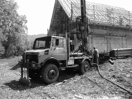 Unimog U1650 mit Bohrmast vor eingerüstetem Haus, Schwarz-Weiss-Aufnahme